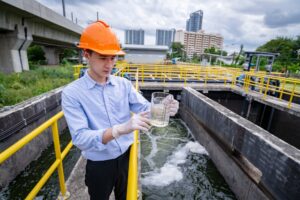 Engineer take water from wastewater treatment pond to check the quality of the water. After going th