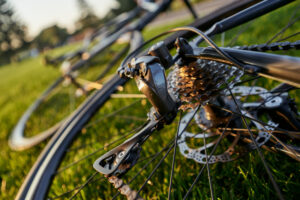 Close up shot of bicycle chain and crank set on profesional black road bike on the grass on a sunny day. Sports, extreme and active lifestyle concept