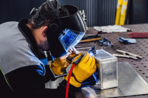 Man performs welding work at his workplace. Welding an aluminum tank with an argon welding machine