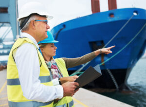 Ship hunt. Two dock workers conferring among themselves while surveying the harbor