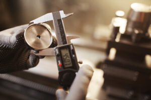 Close-up of man in protective gloves checking the diameter of metal detail with instrument of measurement